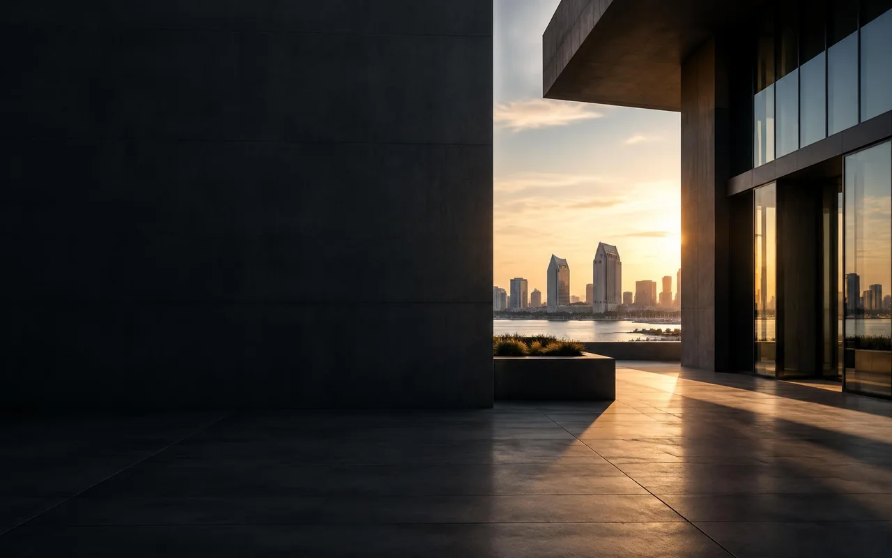 Shaded stone plaza between two modern buildings opening onto the bay and the downtown San Diego skyline at sunset